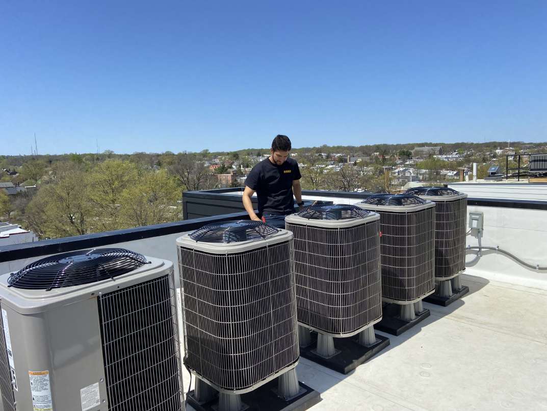 Technician servicing rooftop condensers